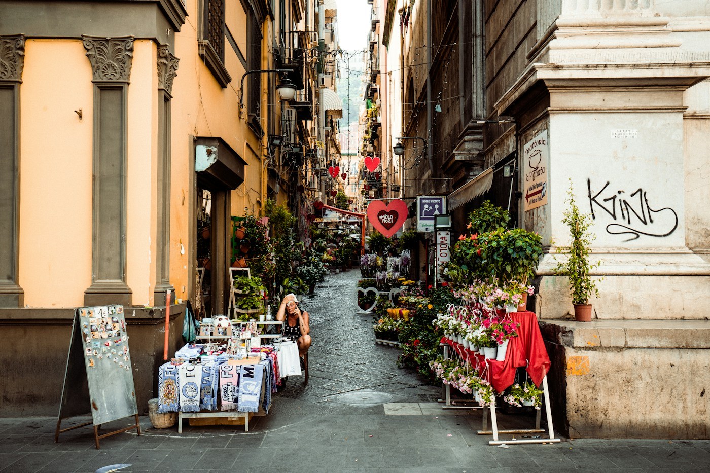 Un vicolo di Napoli con bancarelle e insegne colorate